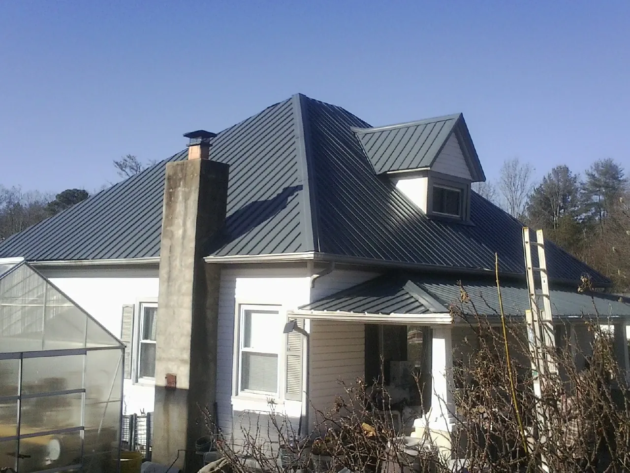 Dark blue standing seam metal roof on a white farmhouse with dormer — Slate & Tile Roof Repair by Roofing Brothers in Church Road