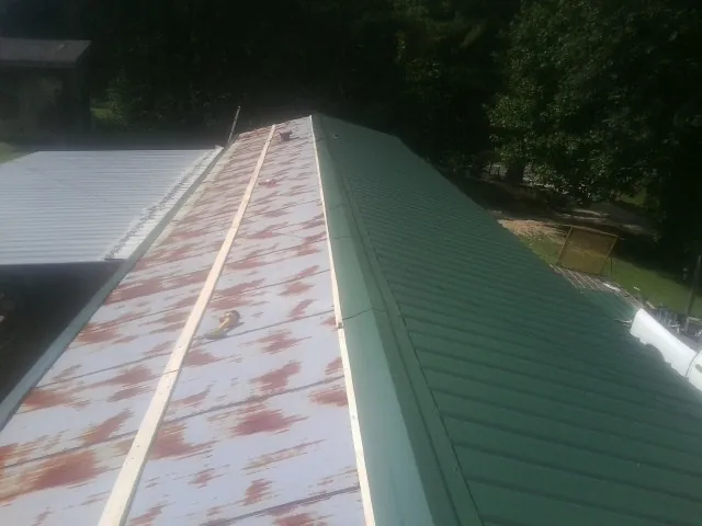 Old rusted panels beside newly installed green metal roofing — Wind Damage Roof Repair by Roofing Brothers in Church Road