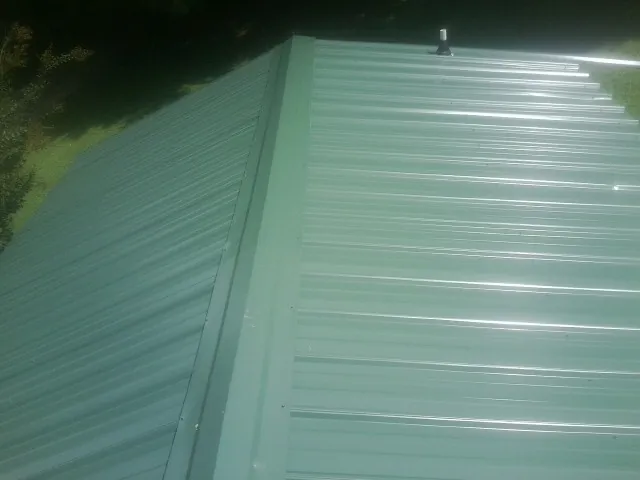 New green metal panels meeting at the ridge of a roof — Flat Roof Repair work by our crew in Church Road