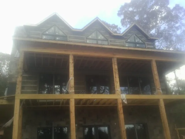 Dormers and porch framing on a large log home under construction — Roof Coating work by our crew in Church Road