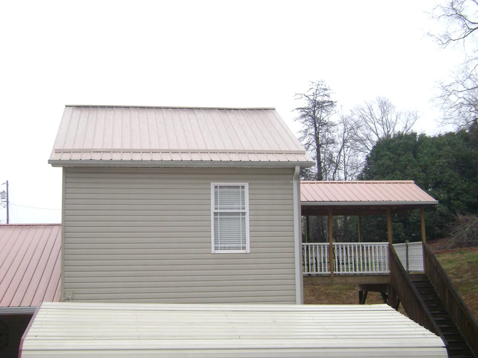 Tan metal roofs on a two story addition and attached porch, from a Roof Replacement job in Church Road
