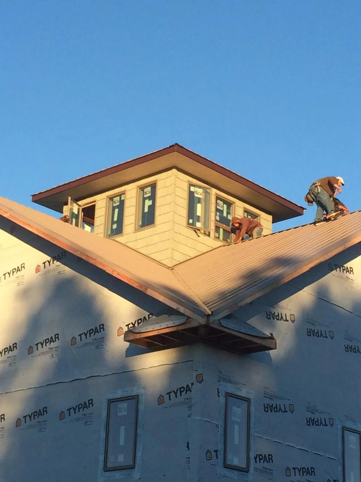 Roofers working around a rooftop cupola on a new metal roof at sunset — Roof Waterproofing in Church Road by Roofing Brothers